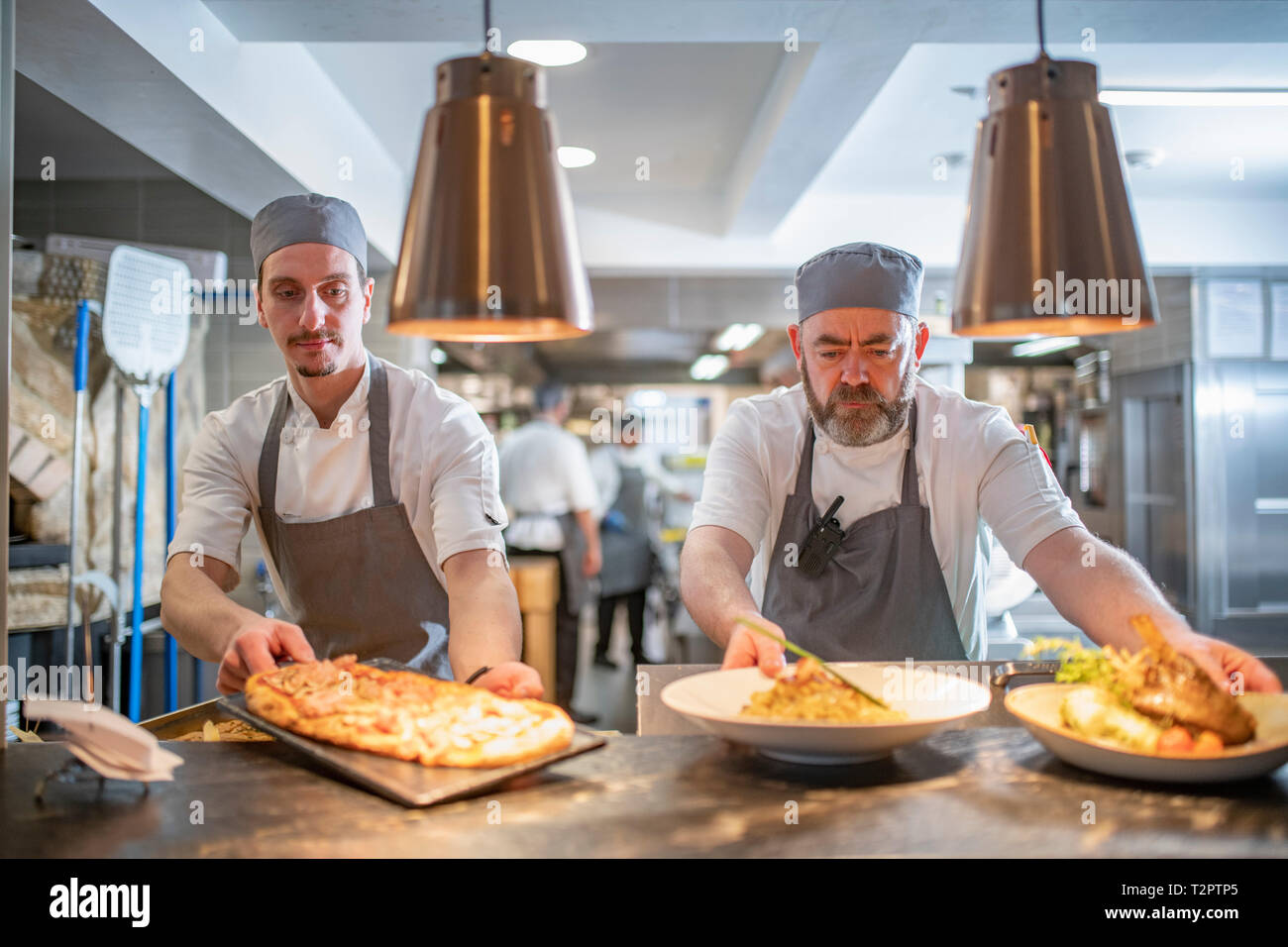 Chefs presenting dishes in Italian restaurant kitchen Stock Photo