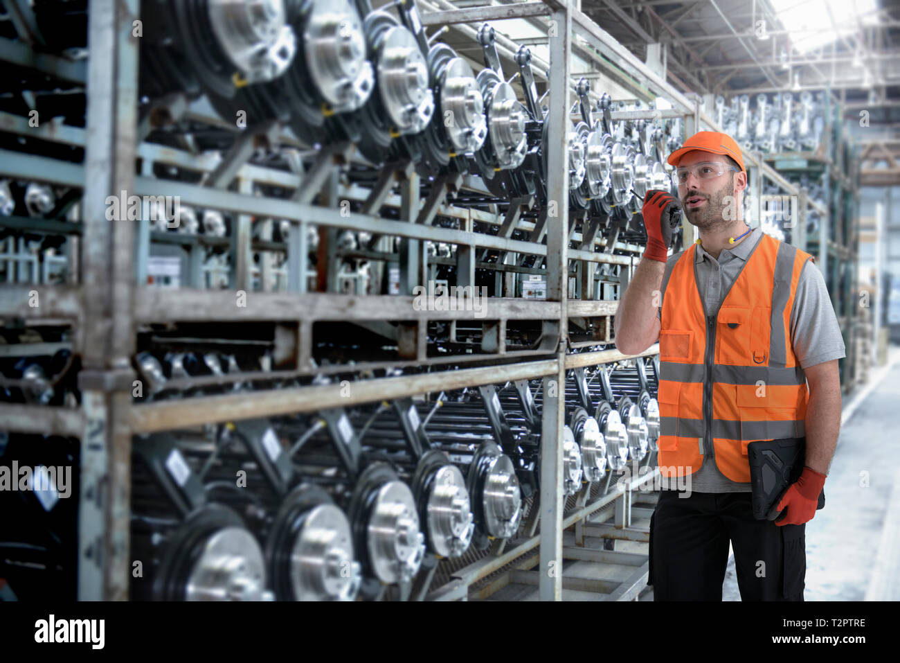 Composite image of worker using walkie talkie in car factory Stock Photo