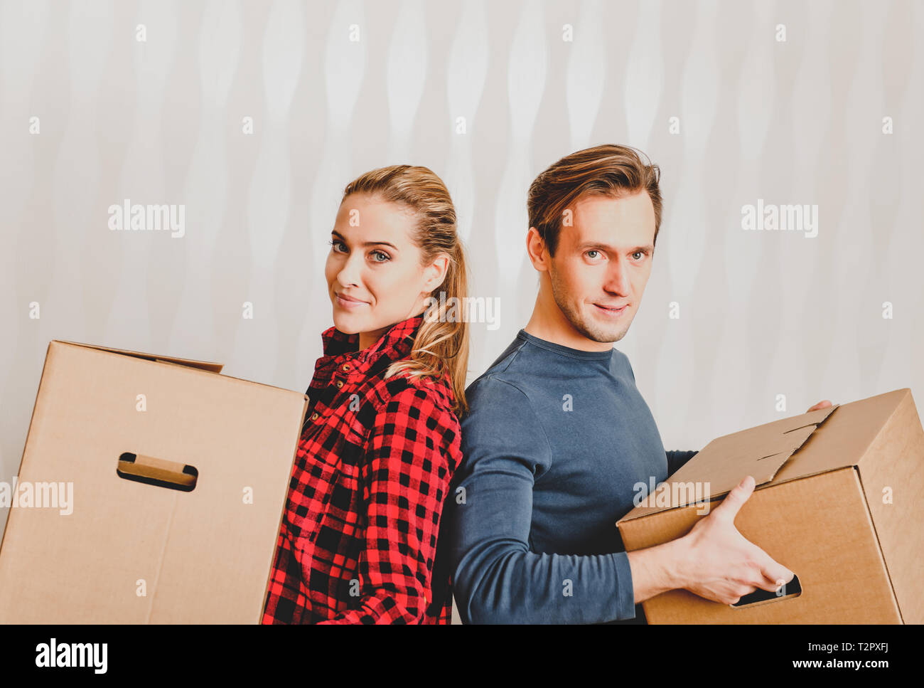 Young couple holding boxes because moving into their new home. Stock Photo