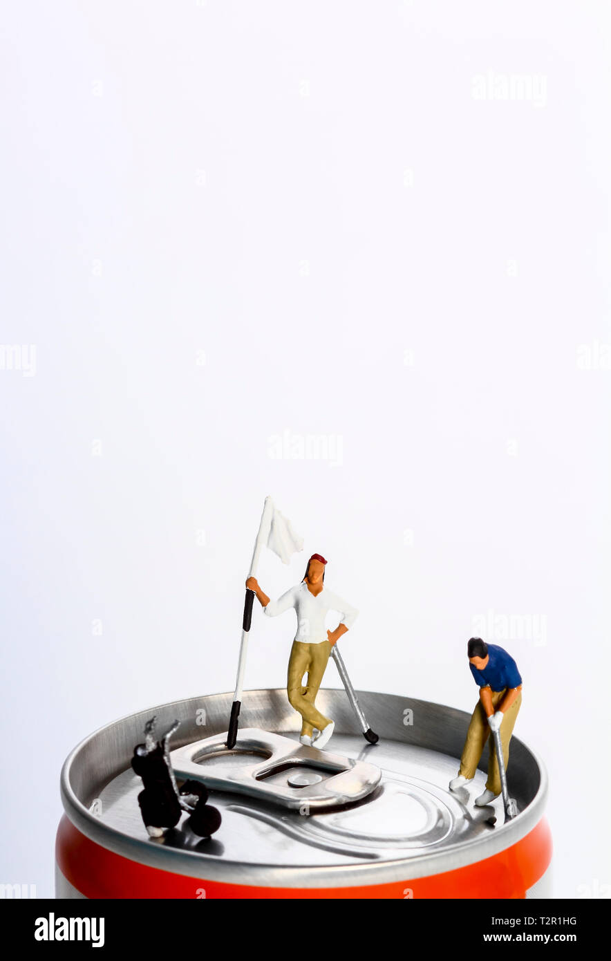 Conceptual diorama image of miniature figures playing golf on the top of a drinks can Stock Photo