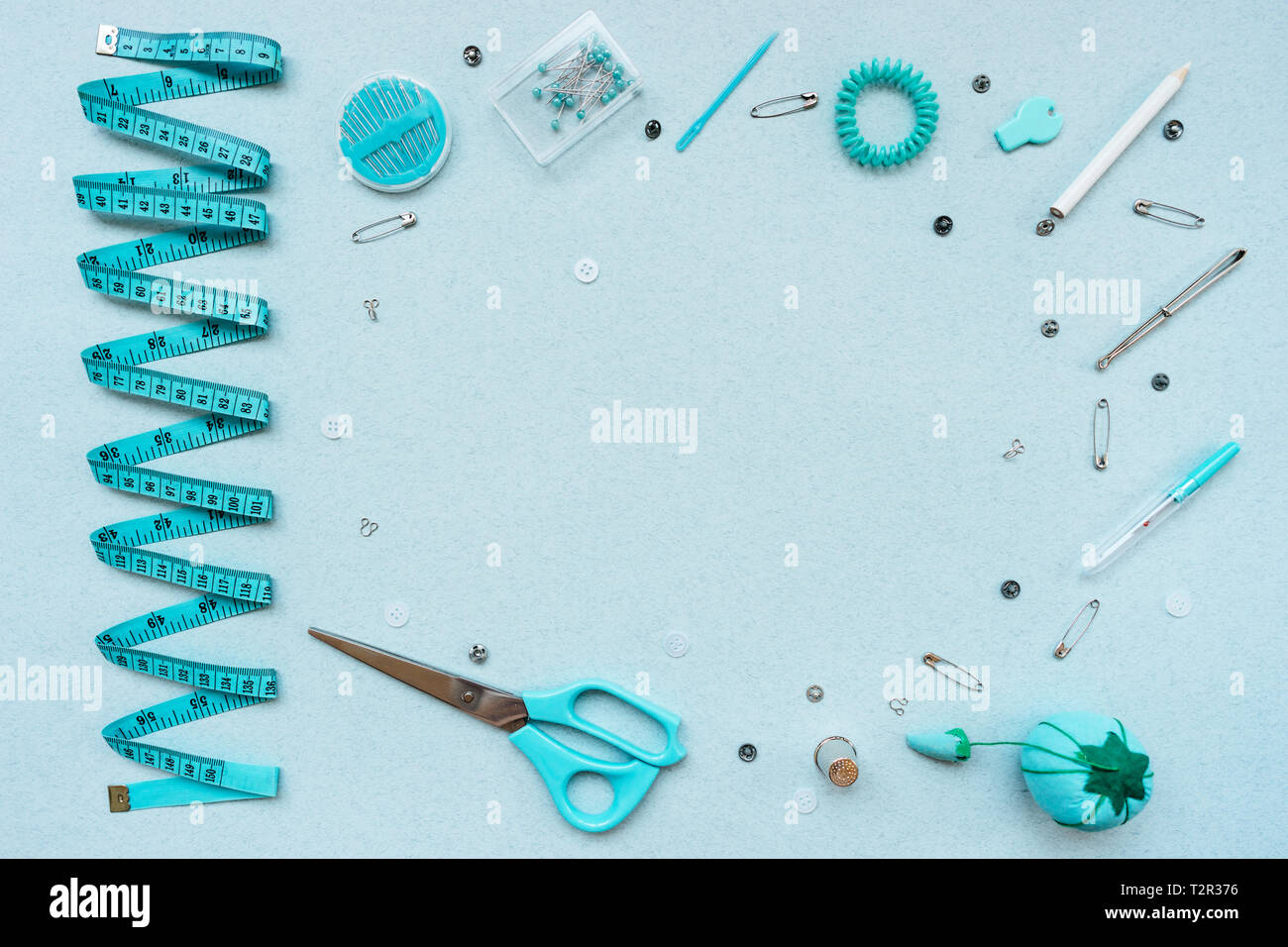 Sewing items - thimble, needle, measuring tape, spools of blue thread,  including pins. Blue fabric for sewing on background Stock Photo - Alamy