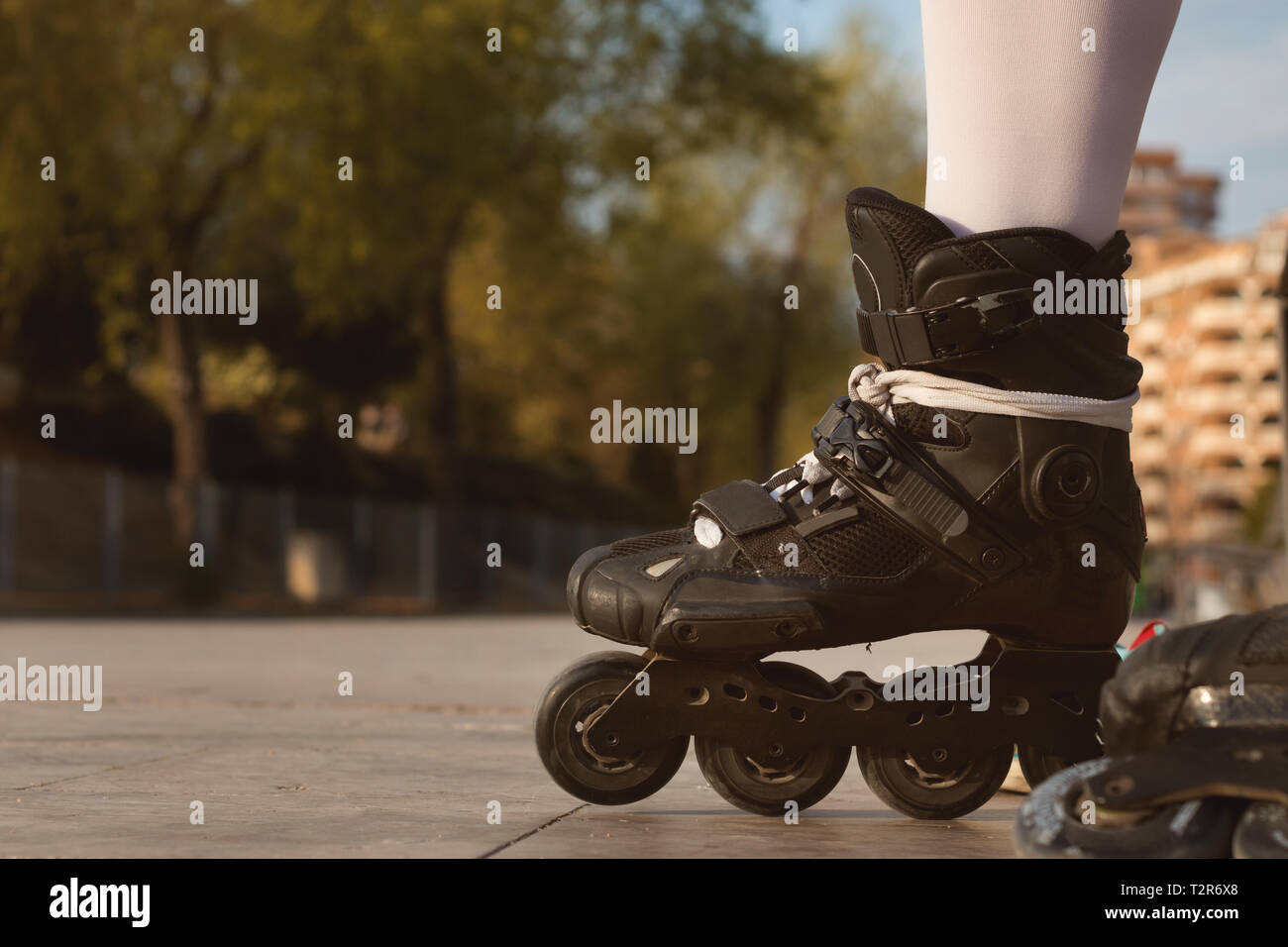 Close-up of black inline skates, overlooking a park out of focus in the background Stock Photo