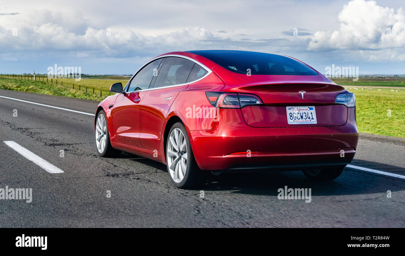 March 20, 2019 Los Angeles / CA / USA - Red Tesla Model 3 driving on the freeway Stock Photo