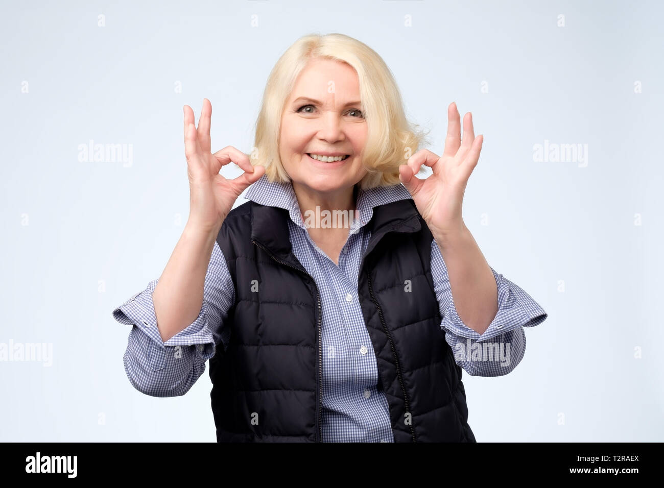 Smiling senior blonde lady gesturing perfect ok sign. Positive human facial emotion Stock Photo
