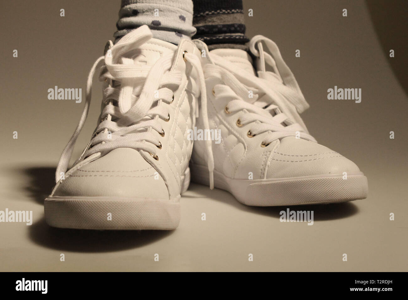 White shoes on white backdrop with mismatched socks and dark shadows. Stock Photo