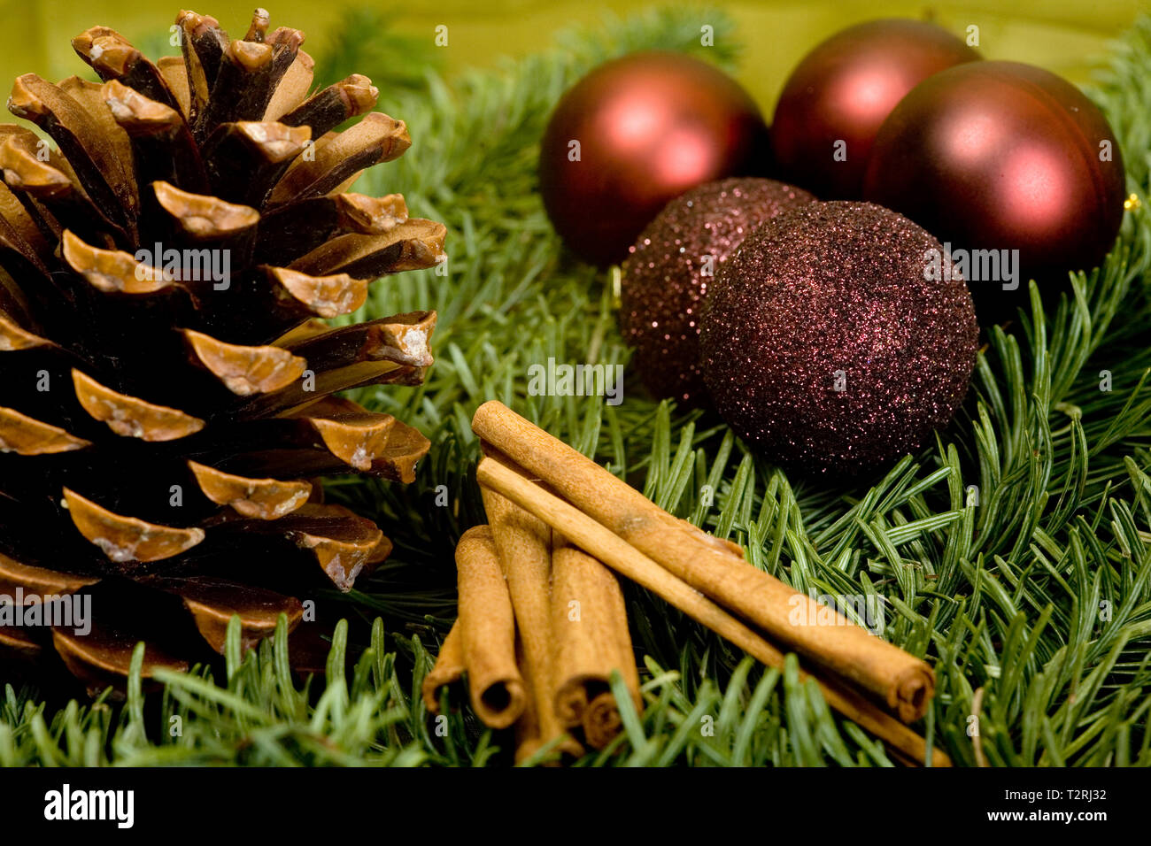 Christmas decoration with fir cones, cinnamon sticks and Christmas balls. Pretty arranged on green fir branches. Stock Photo