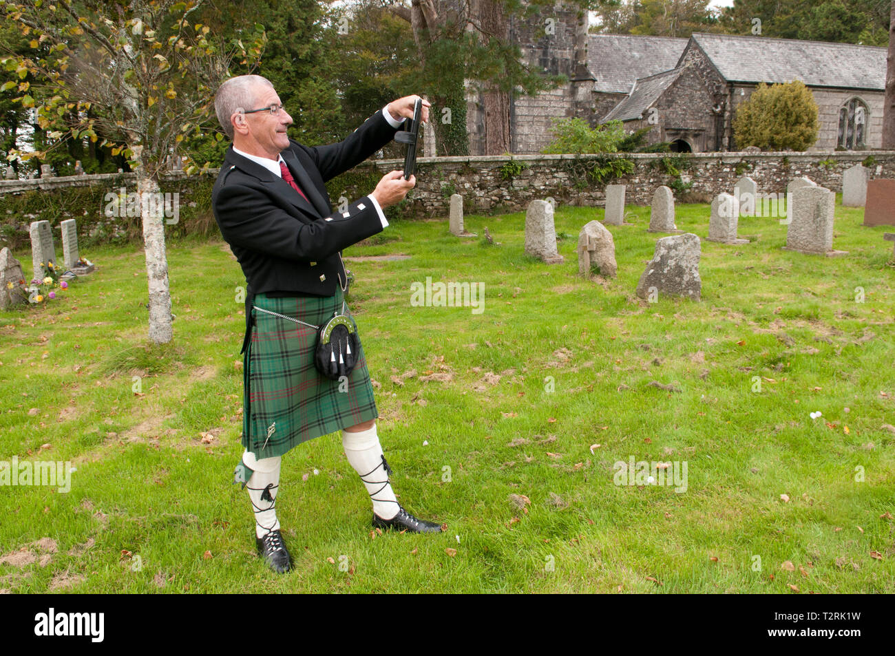 Man wearing a kilt, taking a photograph with his tablet Stock Photo