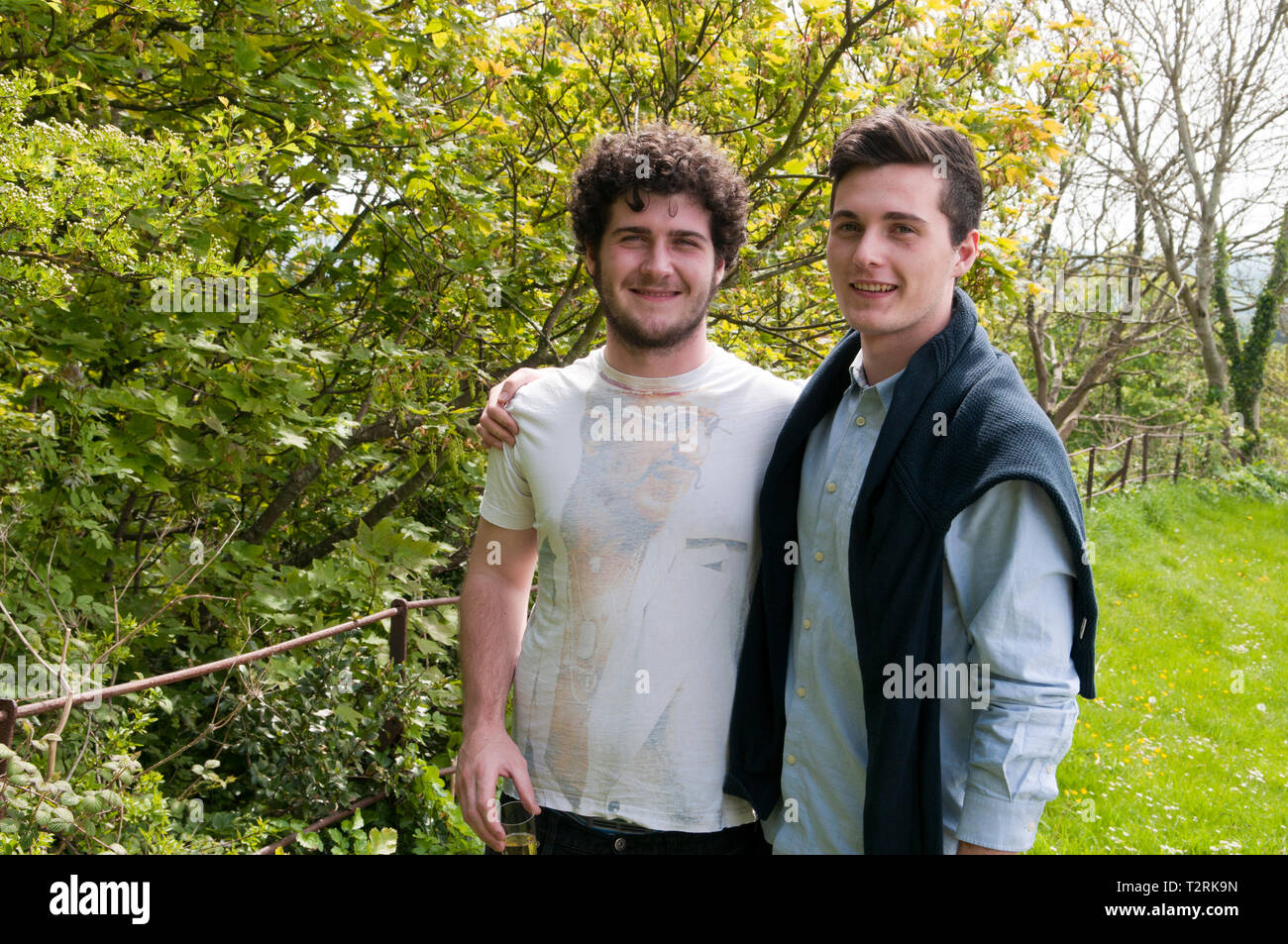 Portrait of two young men smiling with their arms around each other ...