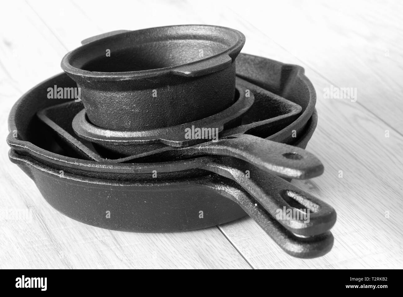 Set of black cast iron pots and pans on a grey wood background Stock