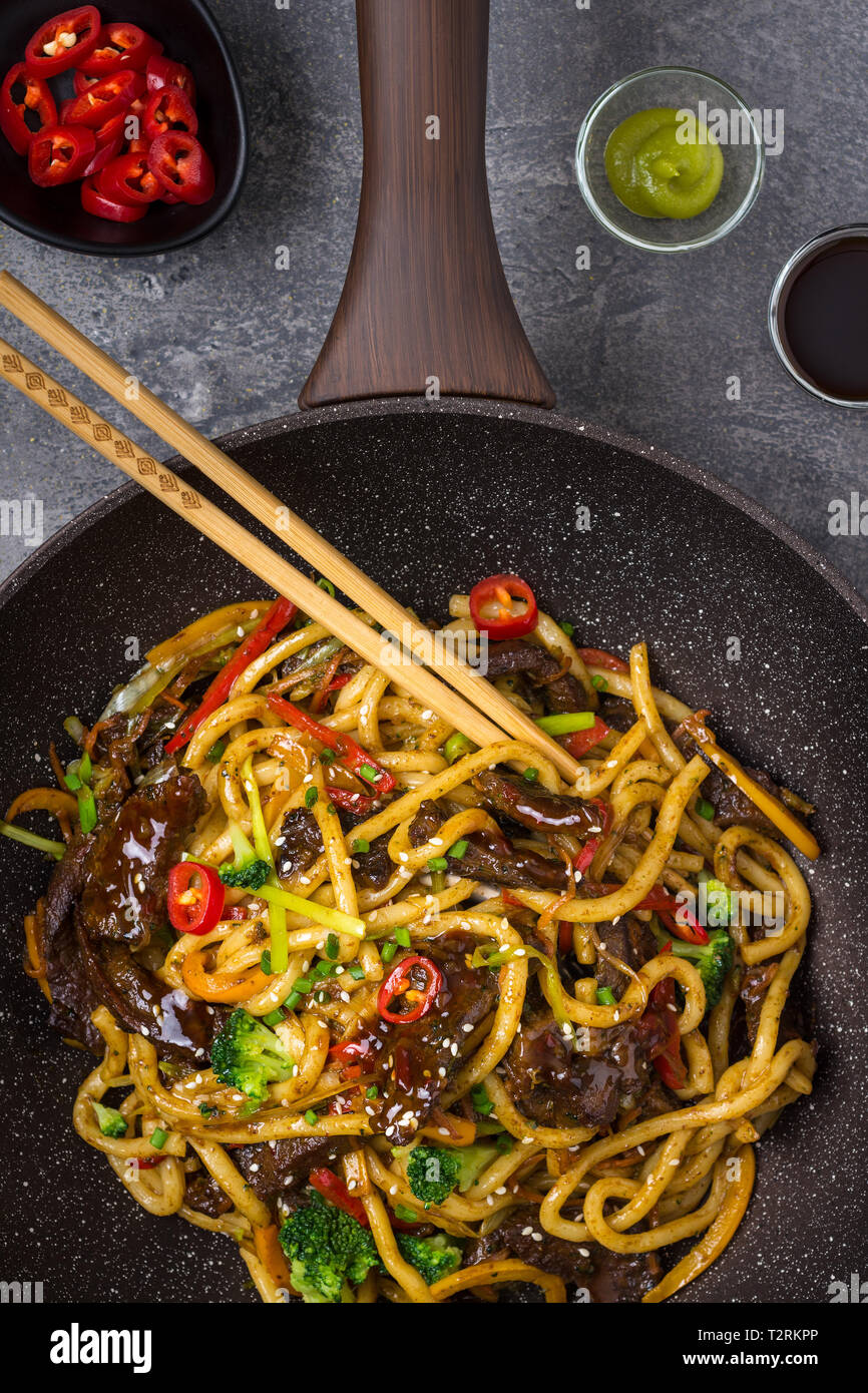 Udon Stir-Fry Noodles with Beef and Vegetables in Wok Pan on Dark Background Stock Photo