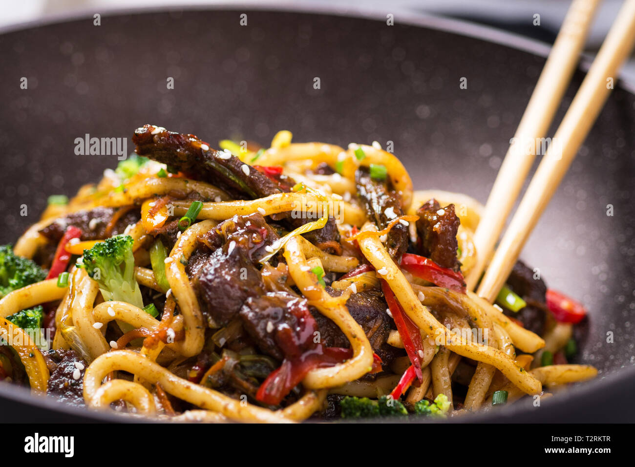 Udon StirFry Noodles with Beef and Vegetables in Wok Pan on Dark