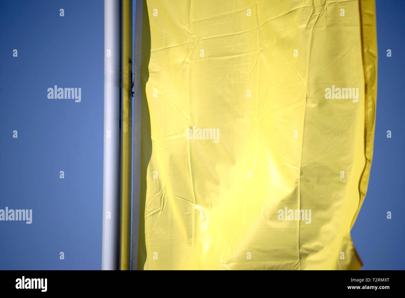 The closeup of a yellow waving banner in front of blue sky background. Stock Photo