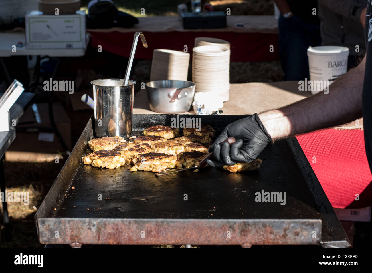 Seafood cook at outdoor festival grilling patties Stock Photo