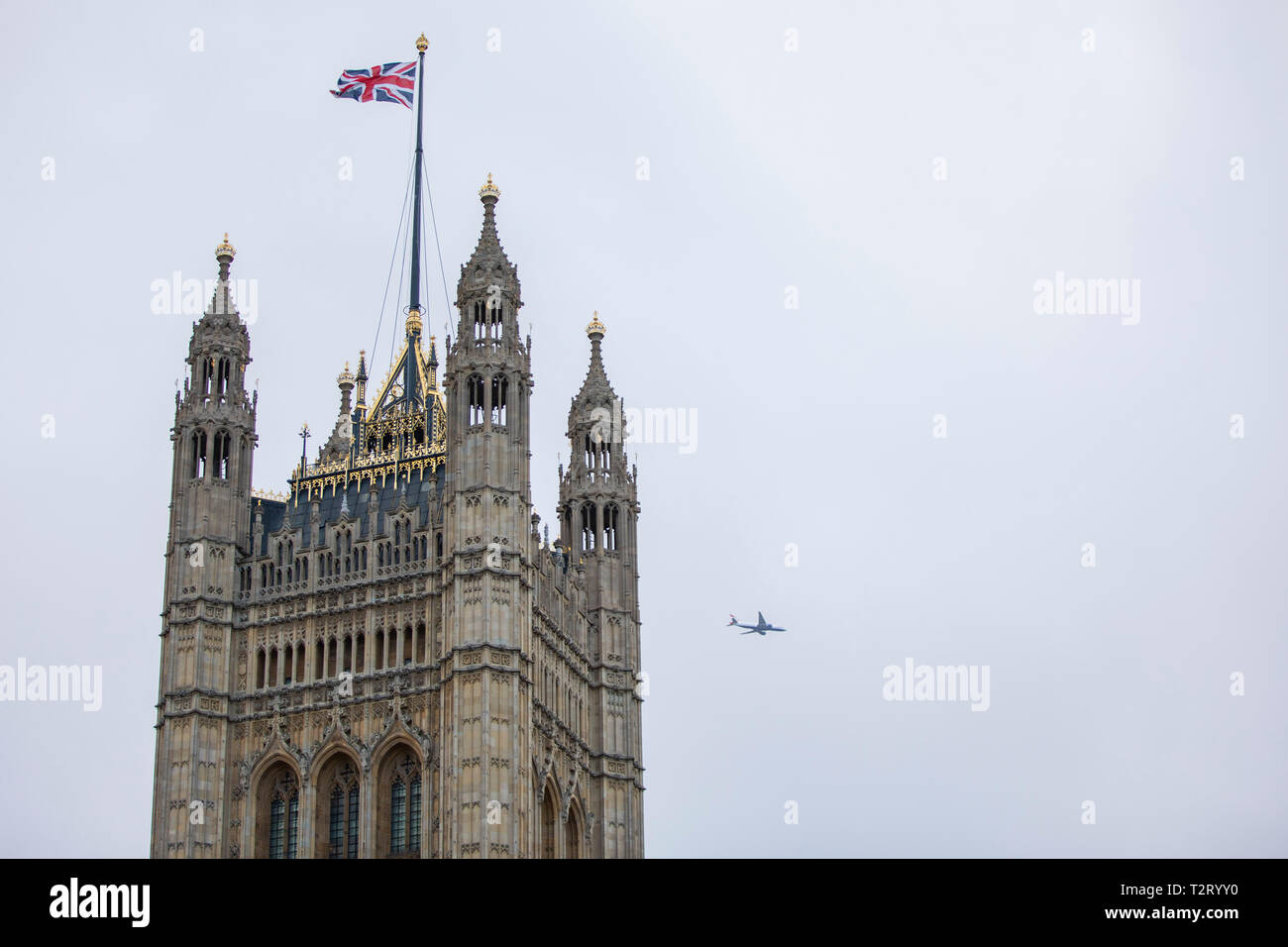 A passenger aeroplane passes the Houses of Parliament tower in December 2018. Stock Photo