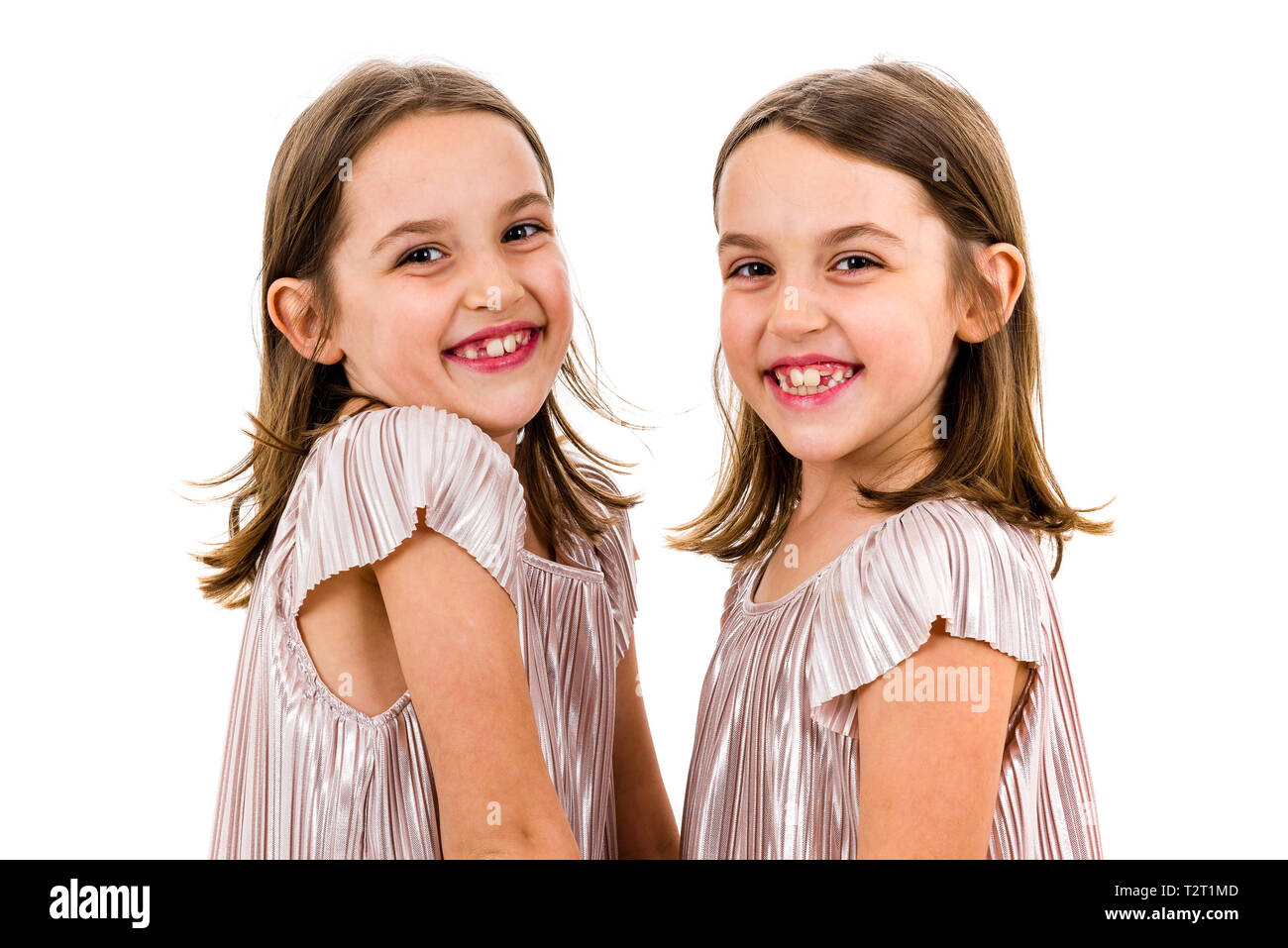 Identical twin girls sisters are posing for the camera. Happy twin