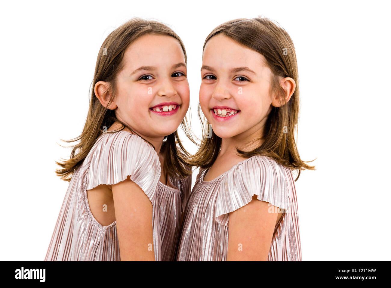 Identical twin girls sisters are posing for the camera. Happy twin