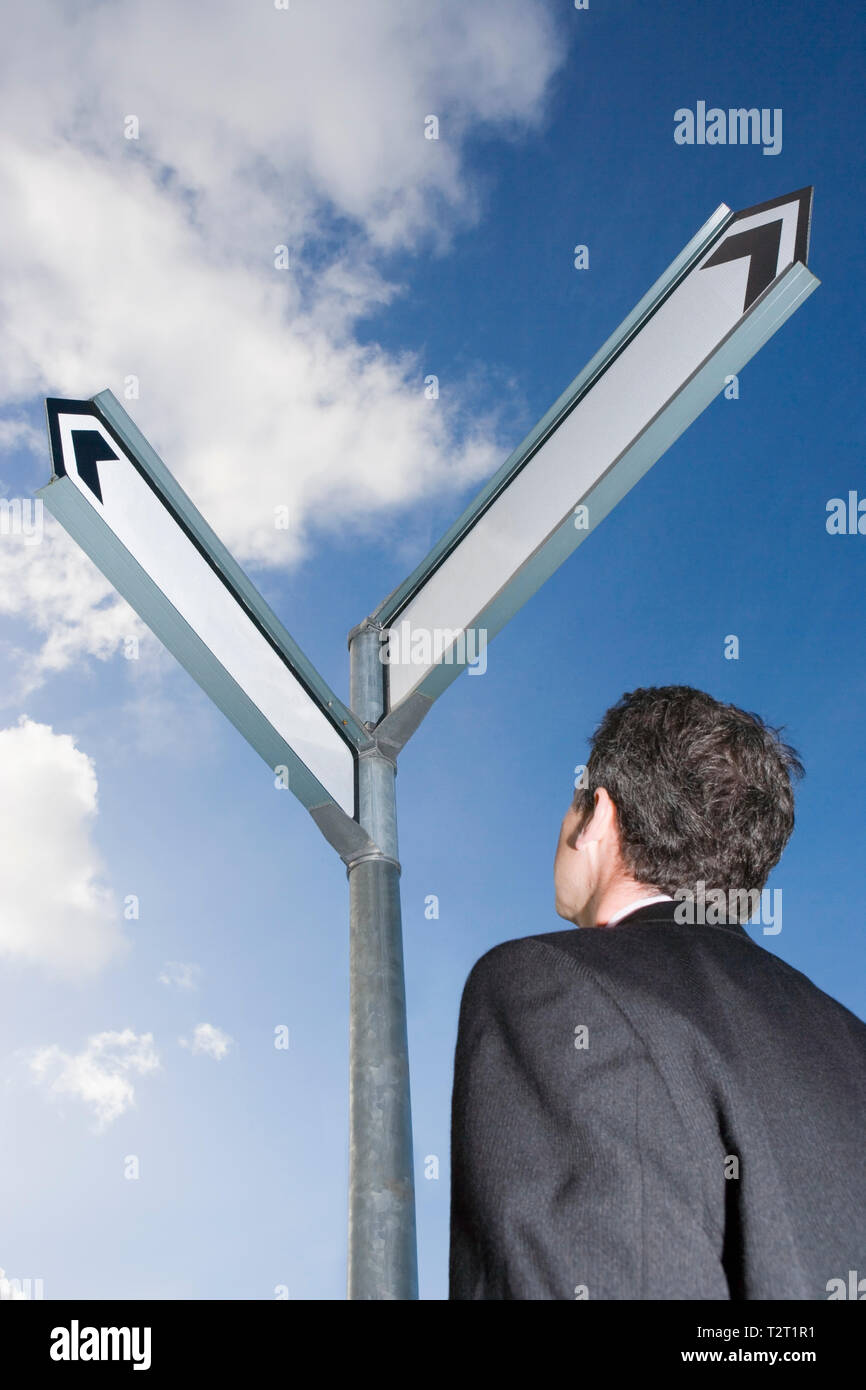 Caucasian businessman standing in front of a blank road sign Stock Photo