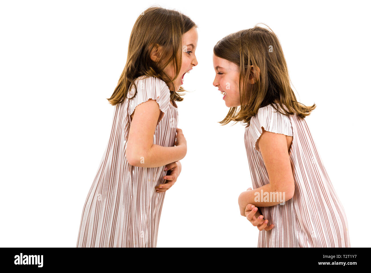 Identical twin girls sisters are arguing yelling at each other. Angry