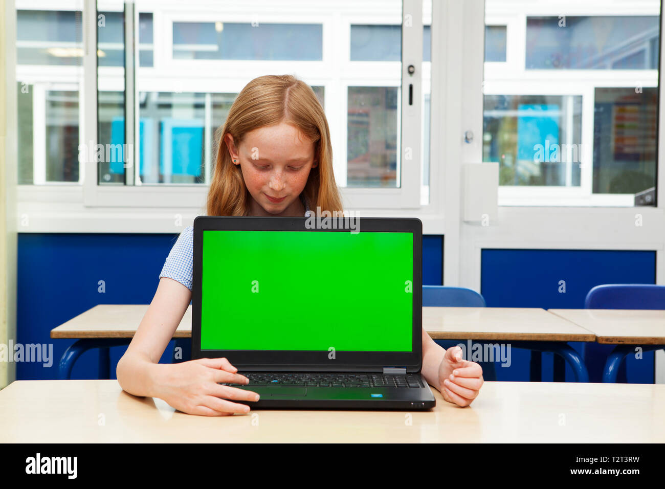 Primary school caucasian girl with her laptop with a green screen Stock Photo