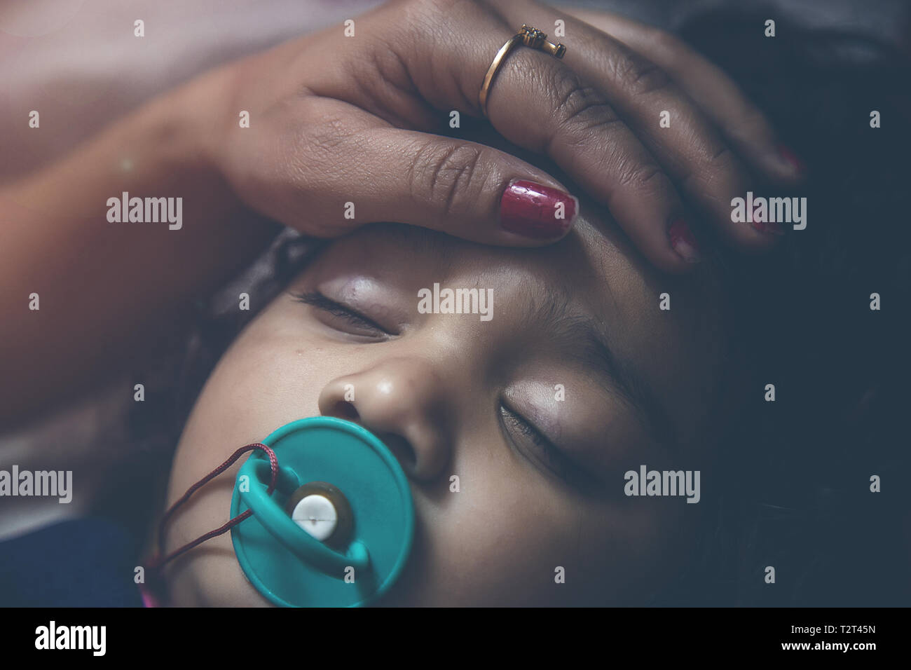 Baby asleep with pacifier while parents caress Stock Photo Alamy