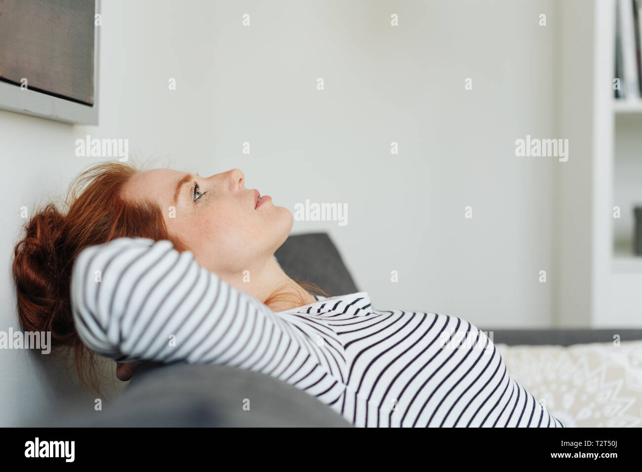 Young Woman Deep In Thought Relaxing On A Sofa With Her Head