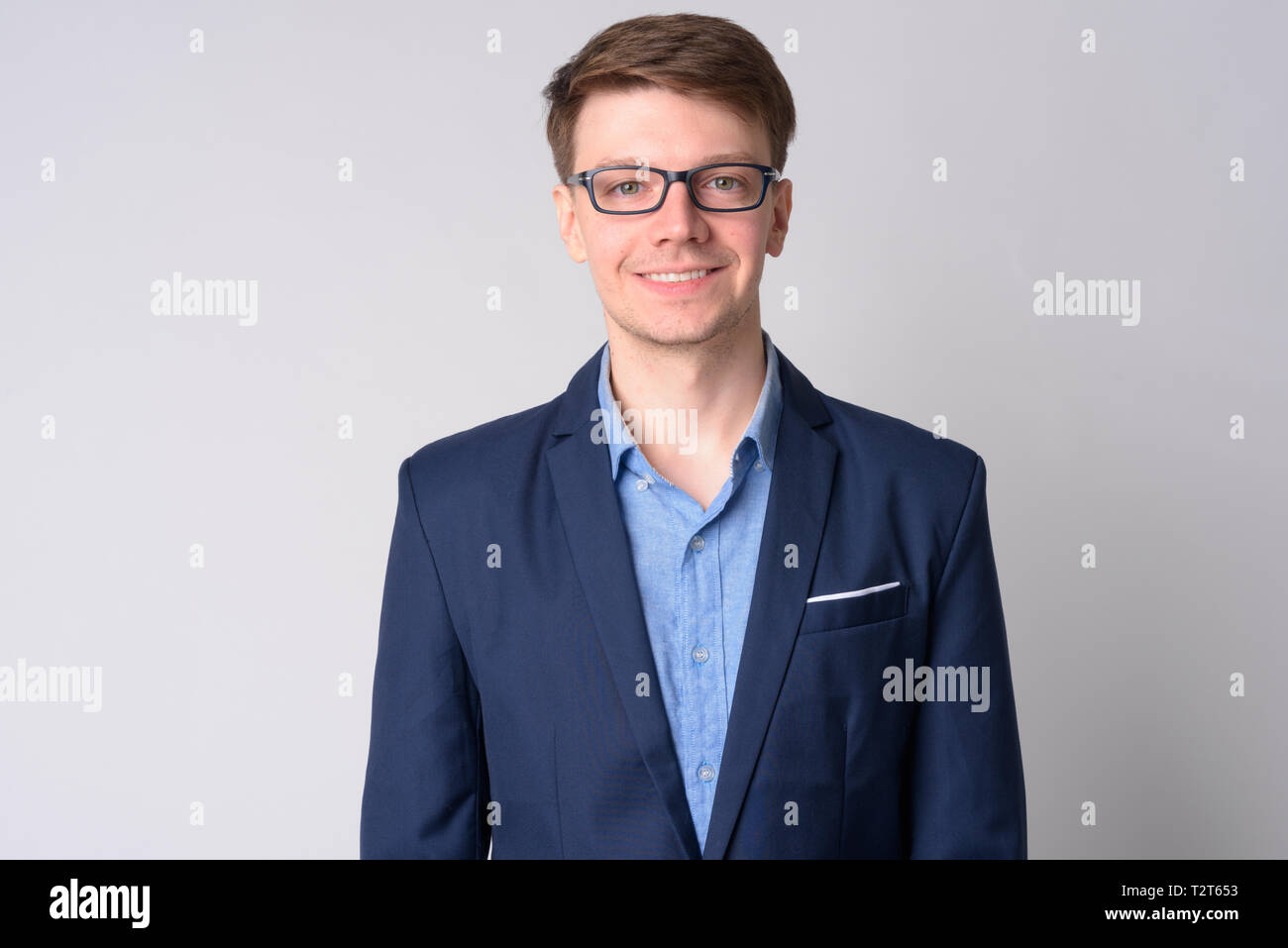 Studio shot of young handsome businessman wearing suit against white ...
