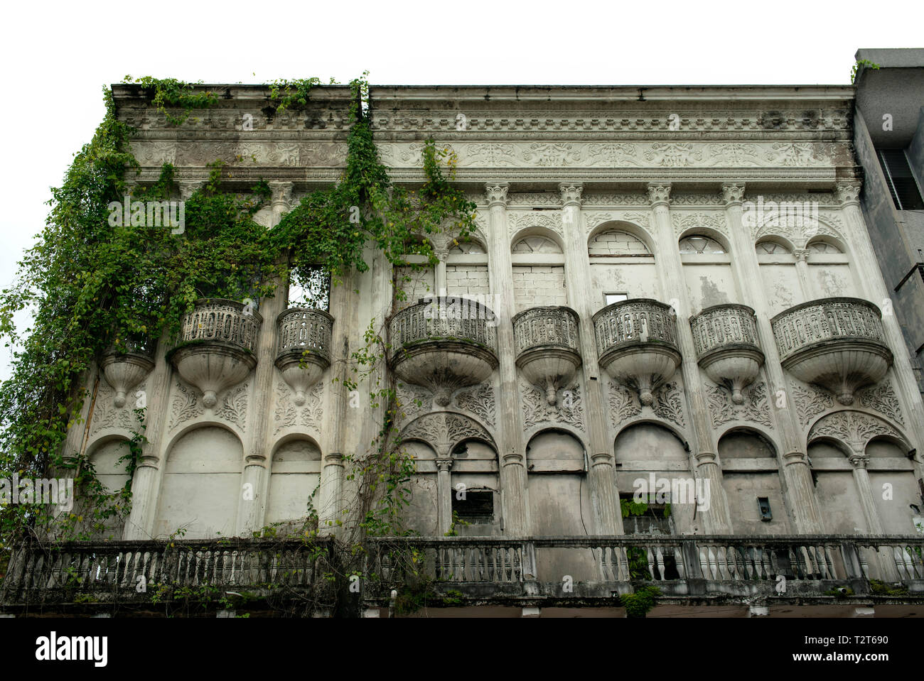 Exterior of abandoned building overgrown with greenery. Located on the main shopping street (Avenida Central) of Panama City, Panama. Oct 2018 Stock Photo
