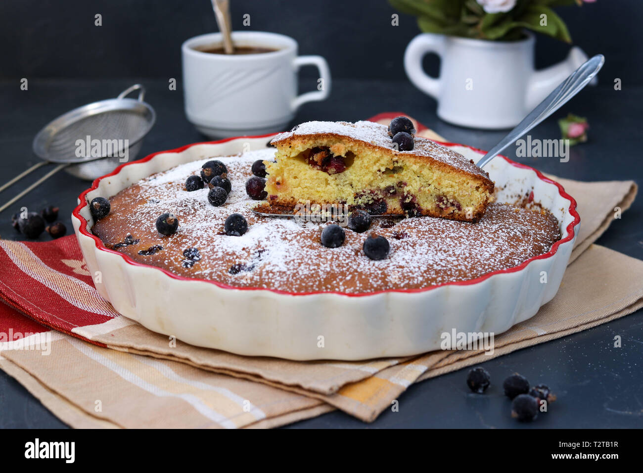 Black currant pie is located in a ceramic form with a cut piece of cake ...