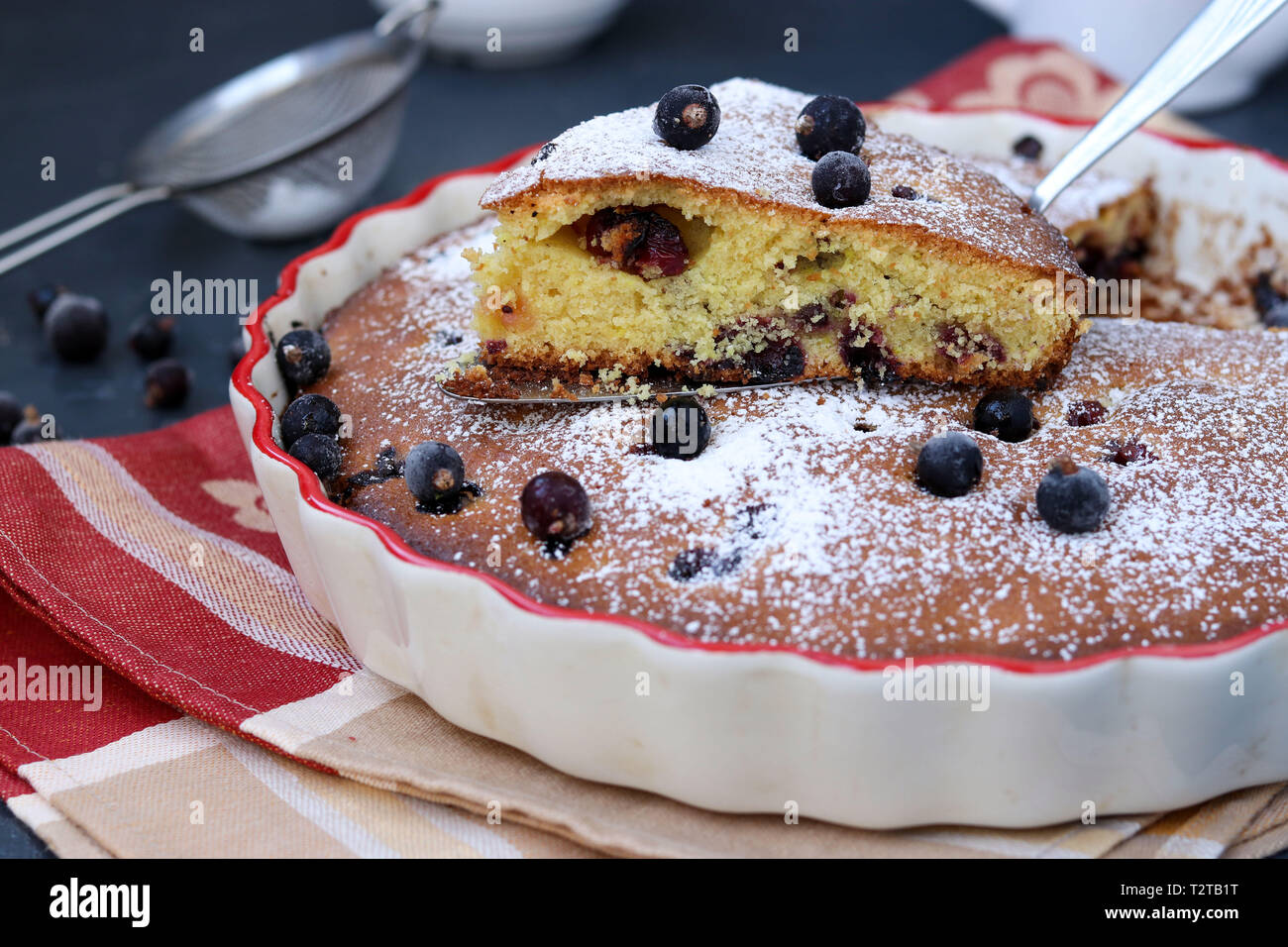 Black currant pie is located in a ceramic form with a cut piece of cake ...