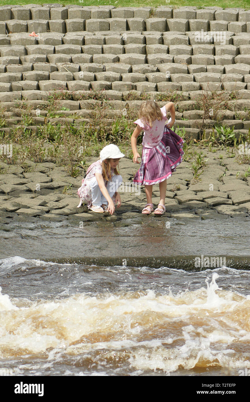 girls playing near fast moving river, water safety, Stock Photo