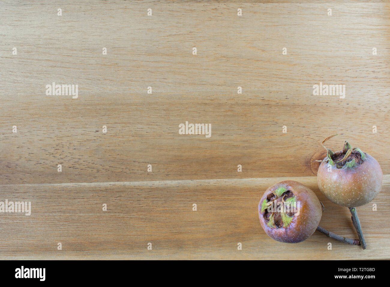composition of fresh medlar fruits on a wooden board with copy space Stock Photo