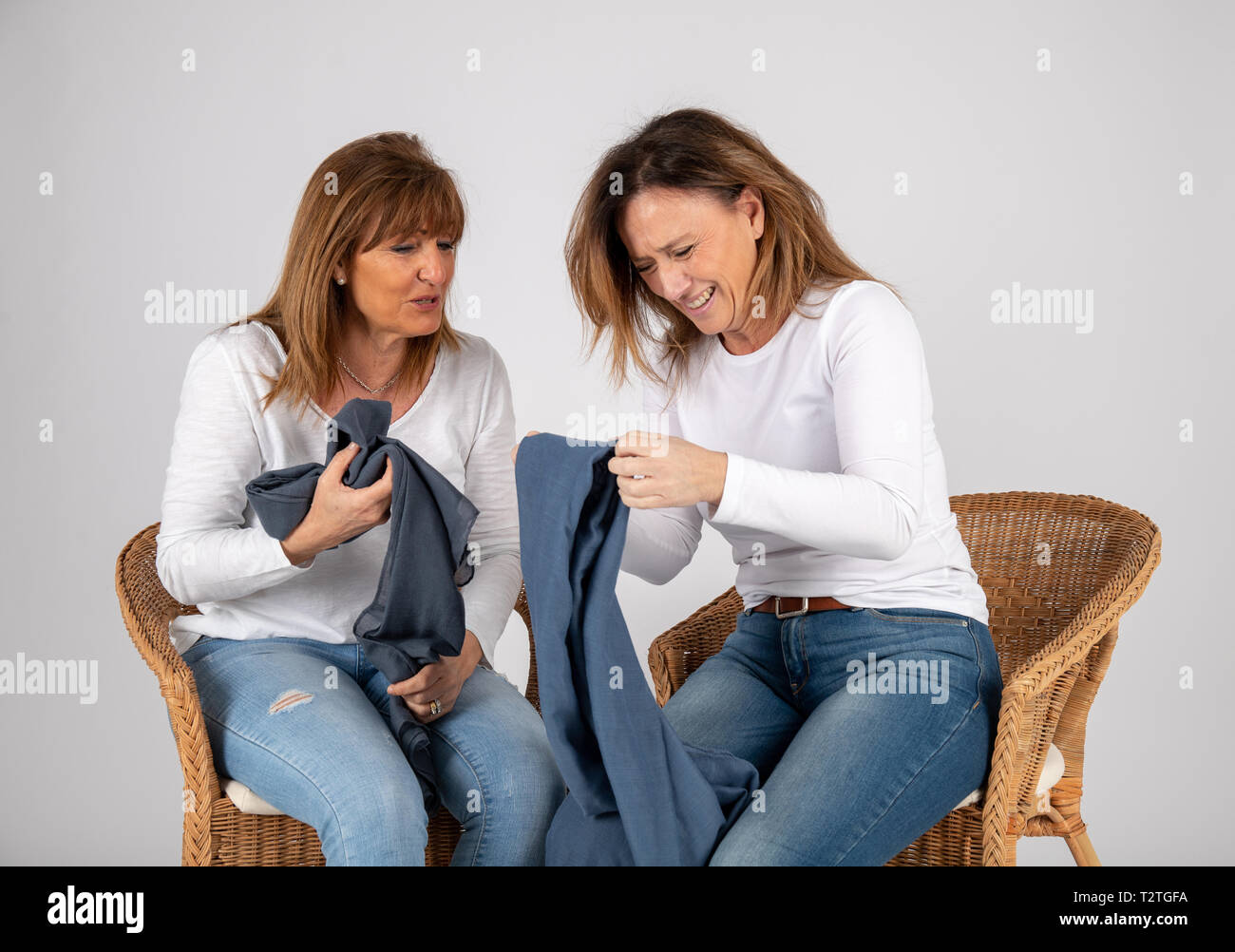 50 year old friends dressed in blue jeans and a white t-shirt laugh together playing with a blue scarf. Stock Photo