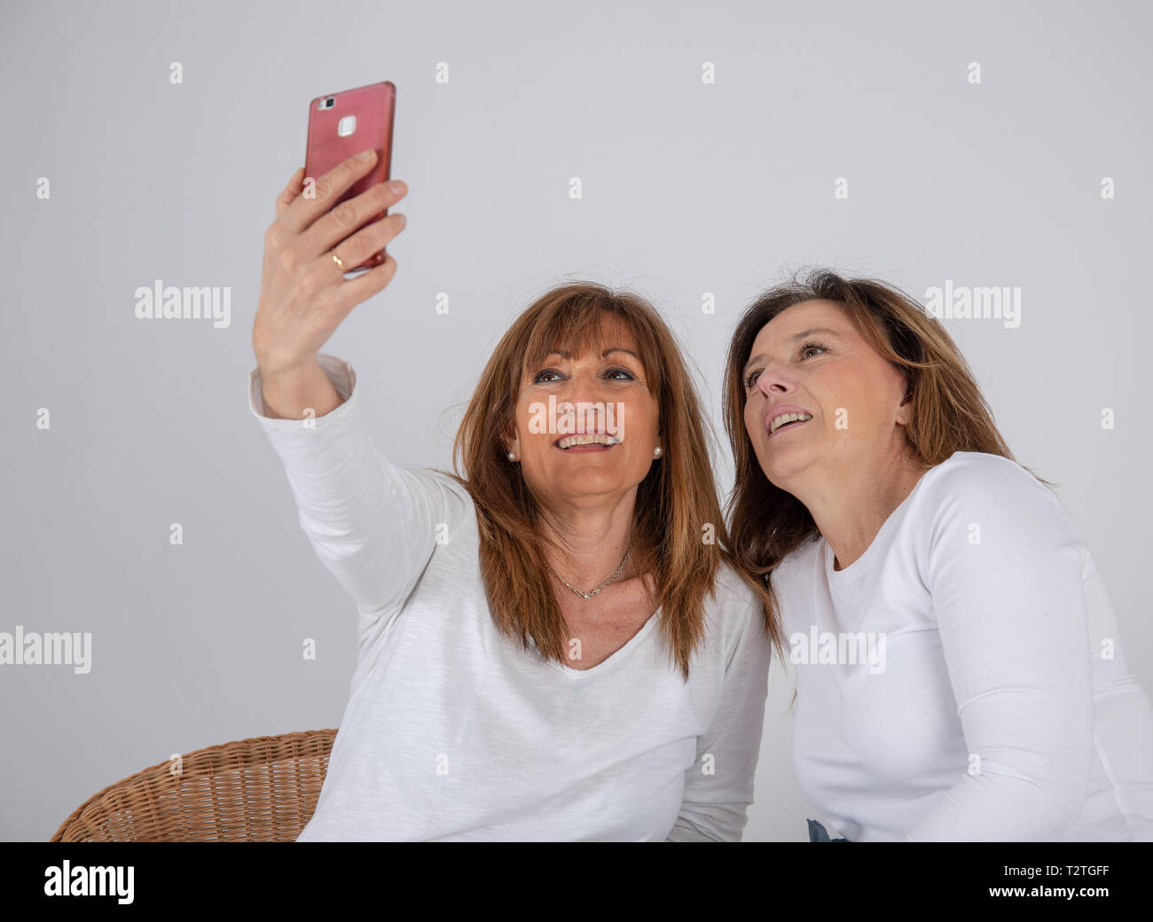 Two 50-year-old friends take a photo with their mobile phone Stock Photo