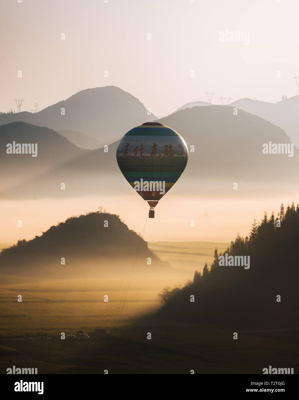 A sunrise hot air balloon ride over the yellow rapeseed fields of Luoping, Southern China Stock Photo