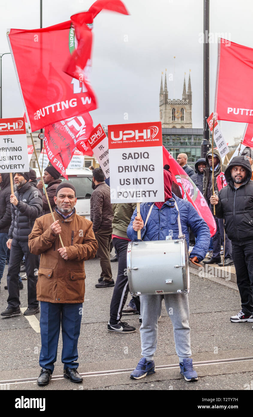 London, UK, 04th April 2019. Minicab drivers block the road on London Bridge protesting against the congestion change on private hire minicabs.  The demonstrators hold and wave flags and placards of UPHD (United Prive Hire Drivers) and IWGB (Independent Workers Union of Great Britain). Credit: Graham Prentice/Alamy Live News Stock Photo