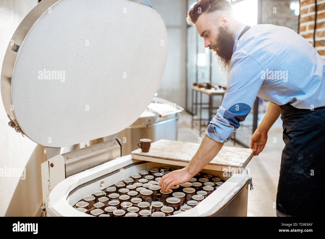Man taking baked ceramic cups from the electric oven at the pottery