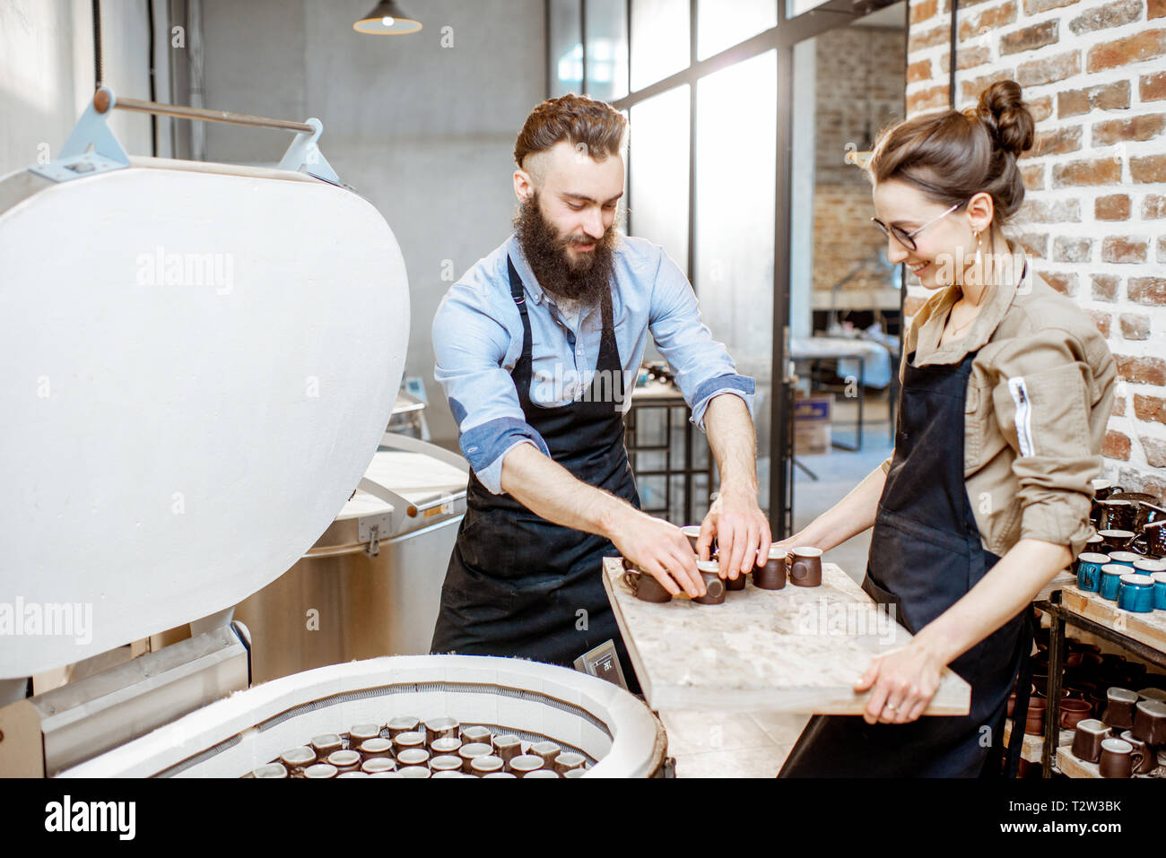 Man and woman taking baked ceramics from eleectric oven, working at the ...
