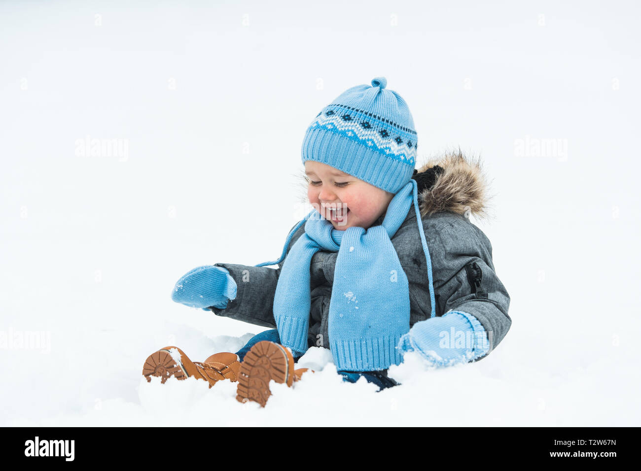 Smiling little baby boy playing in the snow Stock Photo - Alamy