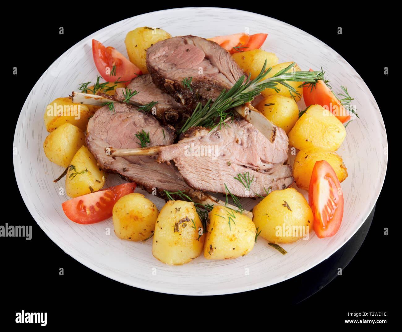 Rack of lamb with fried potatoes and herbs isolated on black Stock