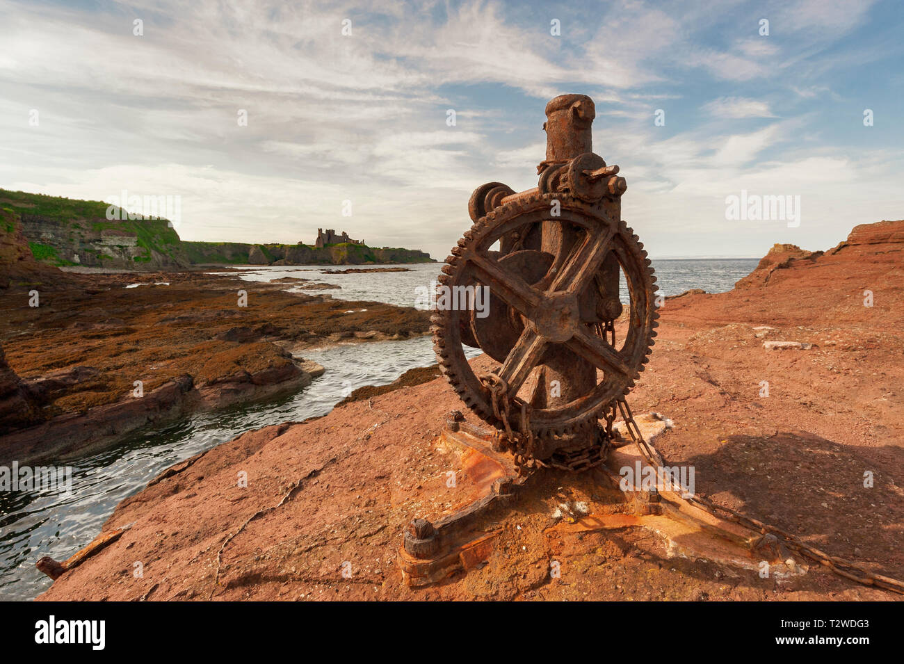 Old Rusty Windlass / Winch at Seacliff Harbour with Tantallon Castle in the distance Stock Photo