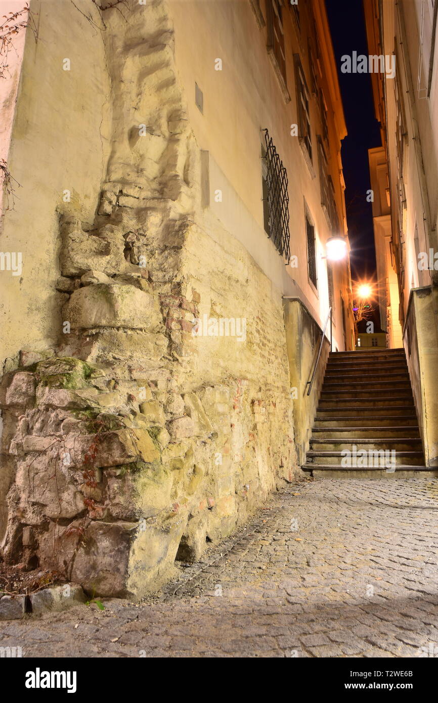 Alleyway, a narrow side street as a passage and connecting path between Grünangergasse and Blutgasse with old walls in the historic city of Vienna. Stock Photo
