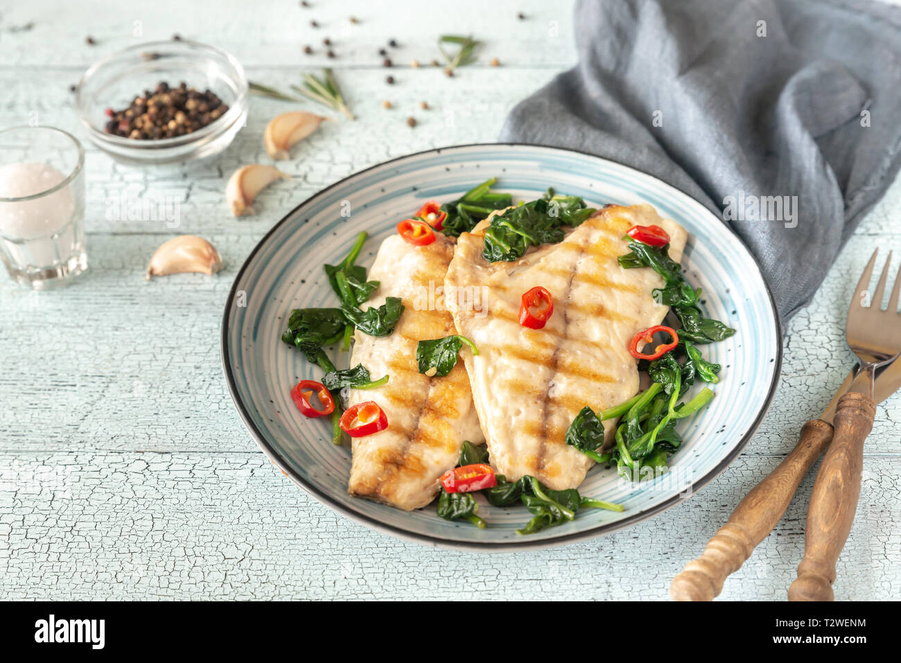 Grilled sea bream fish fillet with spinach and chili pepper Stock Photo