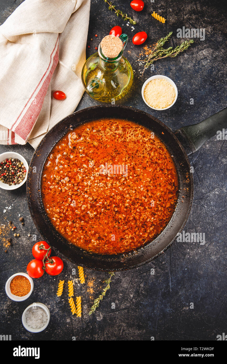 Classic italian bolognese sauce stewed in stewpot with ingredients on