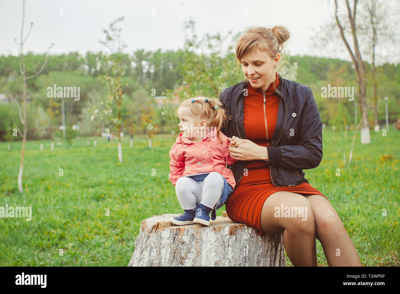 little girl sitting on a stump in the summer garden Stock Photo - Alamy