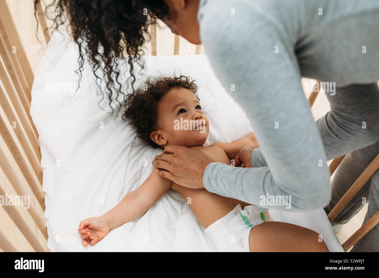 Mother putting her newborn baby boy into crib Stock Photo Alamy
