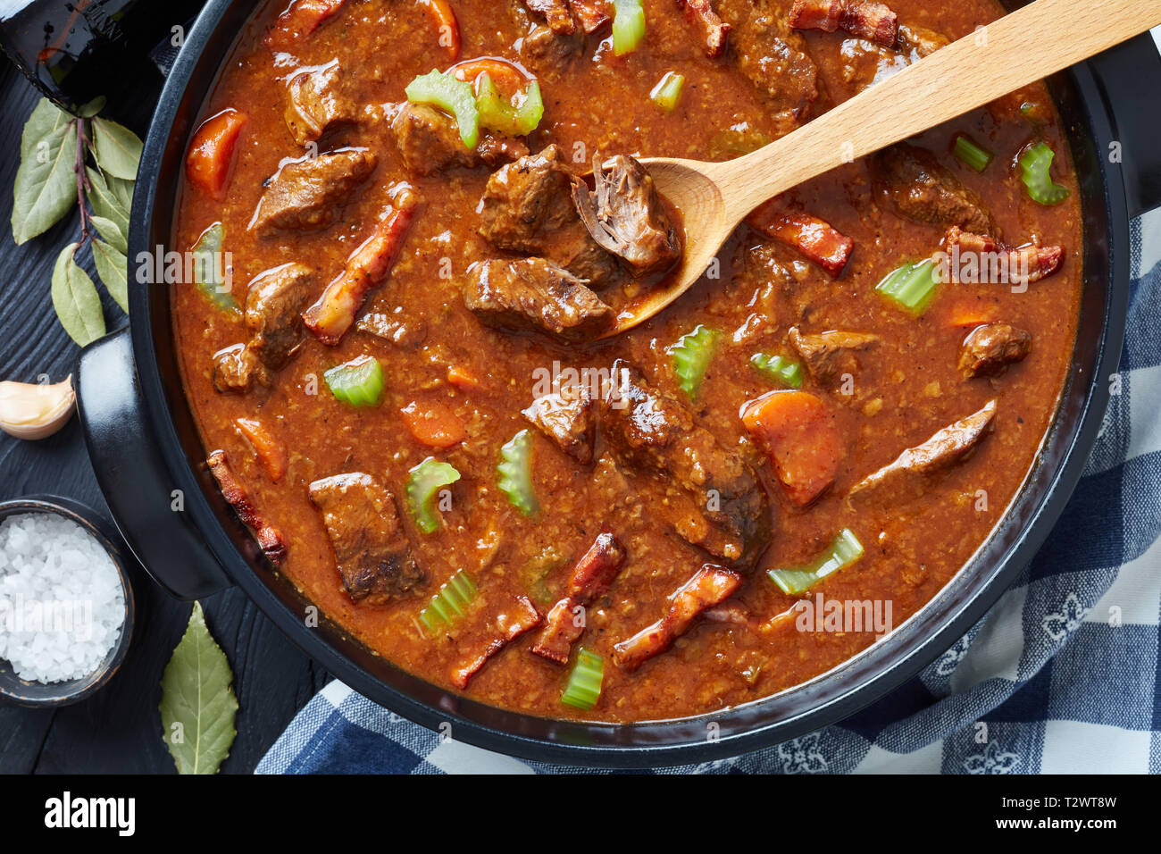 traditional irish beef and beer stew with carrots, celery stalk, carrots and spices in a dutch oven on a black wooden table, view from above, flat lay Stock Photo