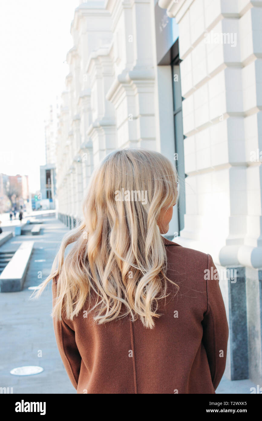 Stylish fashionable woman wearing coat with curly blonde hair, street style photo Stock Photo