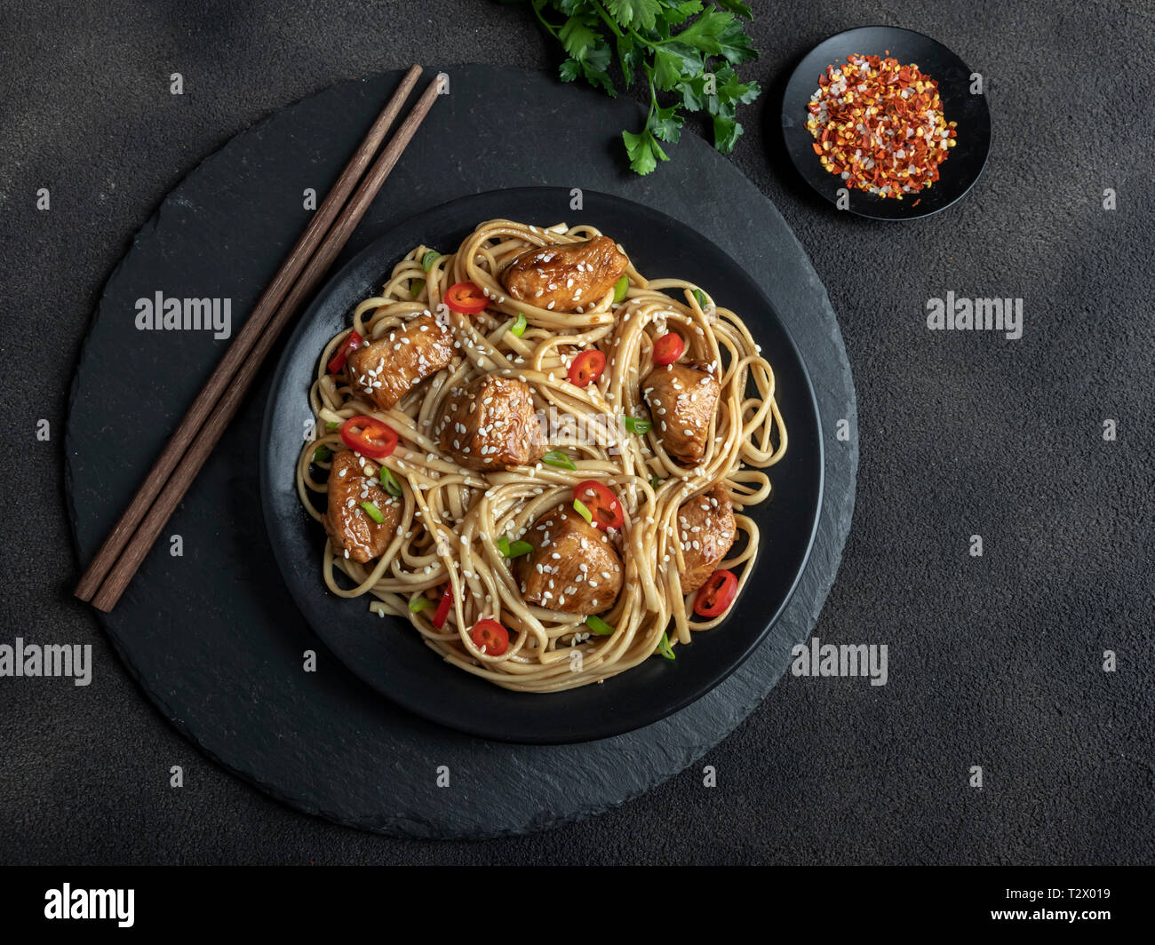 Chicken teriyaki with asian noodles udon , sesame, rustic stone background. Closeup. Chinese