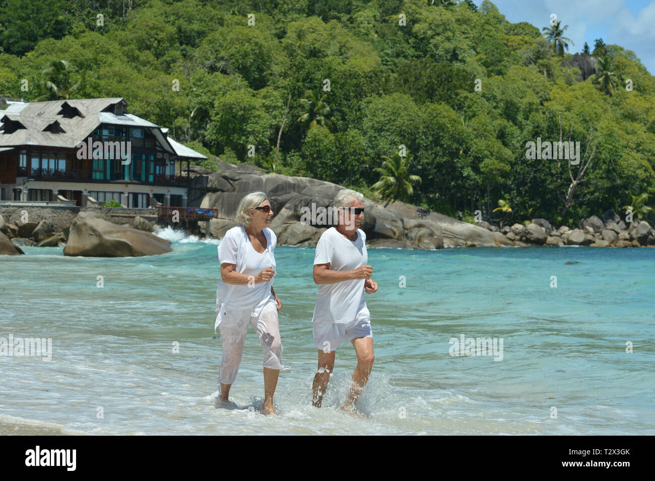 Happy elderly couple running  on sandy beach Stock Photo