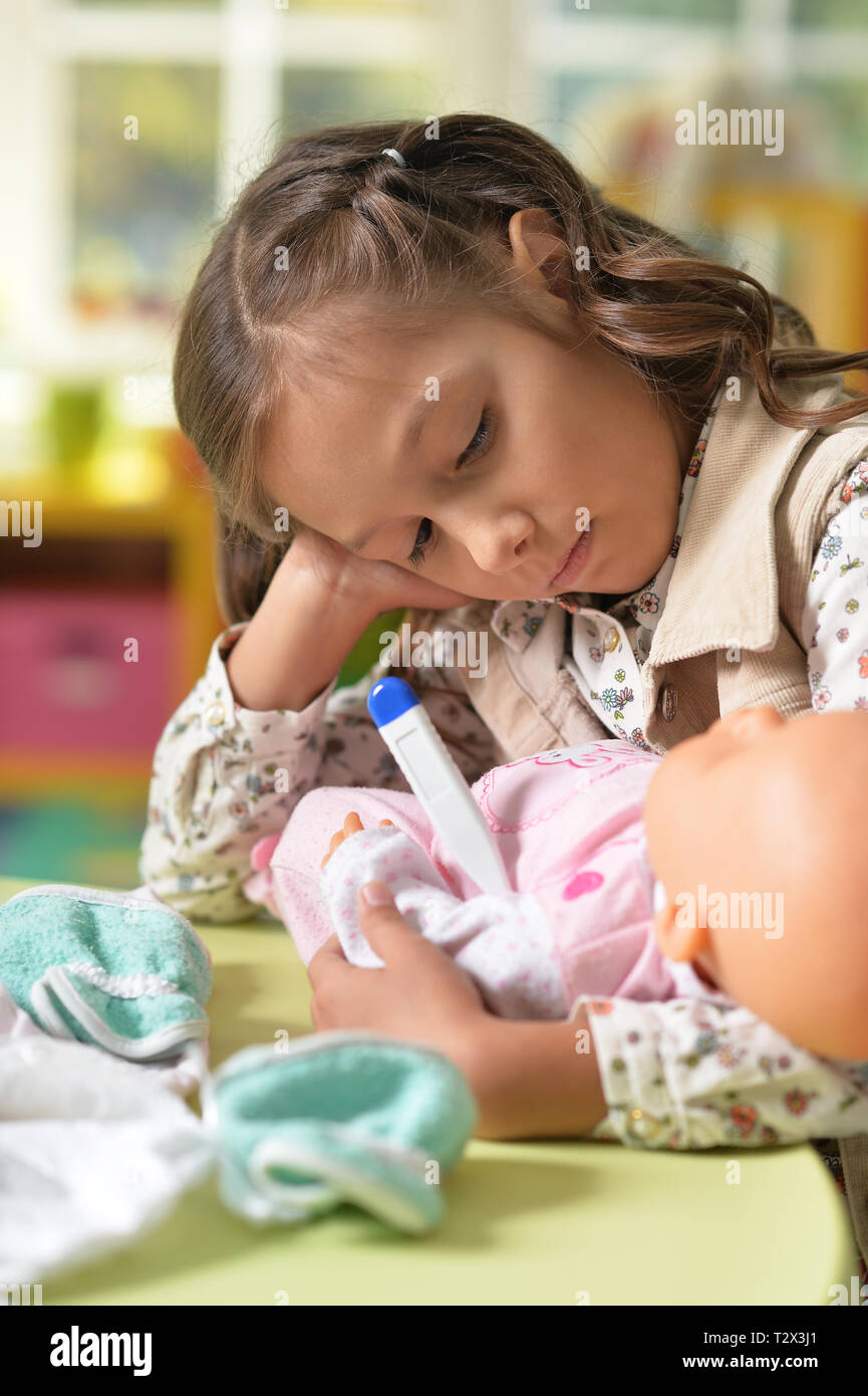 Portrait of cute little girl playing with doll Stock Photo - Alamy